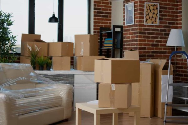 Nobody in empty living room with cardboard packaging Nobody in empty living room with cardboard packaging at new home, furniture things in stack of carton boxes. No people in household property with package cargo to move in, real estate.